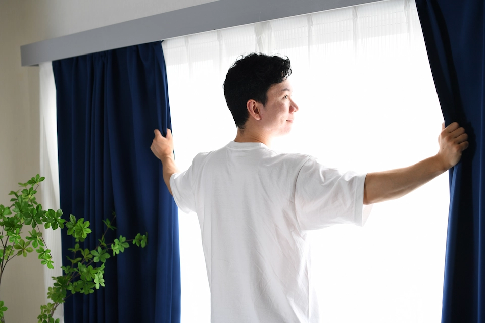 男性がカーテンを開ける