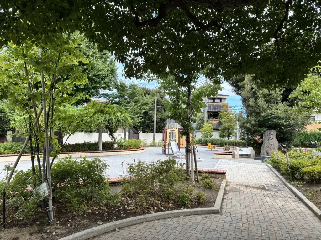 西片公園の敷地内。遊具やベンチ、木陰が充実